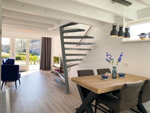 Ein moderner Essbereich mit Holztisch, Stühlen und einer markanten Wendeltreppe.