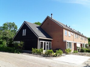 Ein zweistöckiges Wohnhaus mit einem dunkel gefärbten Vorderteil und einem Ziegelteil.