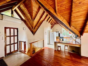 Ein großzügiges Loft mit hoher Decke, Holzbalken, einer Küchenzeile und einer großen Schiebetür.