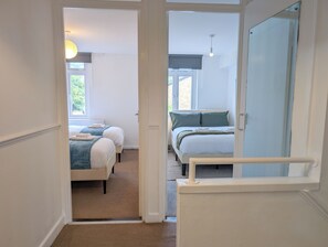 Ein Schlafzimmer mit zwei Betten, einem Fenster und einer Tür zu einem anderen Raum.