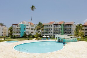 Ein Resort mit mehrstöckigen Gebäuden, einem zentral gelegenen Pool und Palmen.