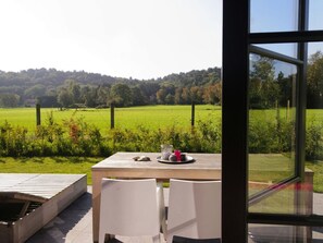 Ein Tisch mit Stühlen und Blick auf ein grünes Feld und Bäume.