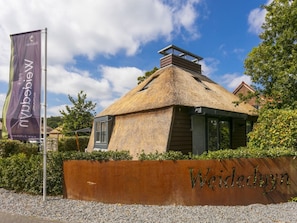 Ein Gebäude mit einem Strohdach und einem Holzschild mit der Aufschrift 'Weidebyn'.