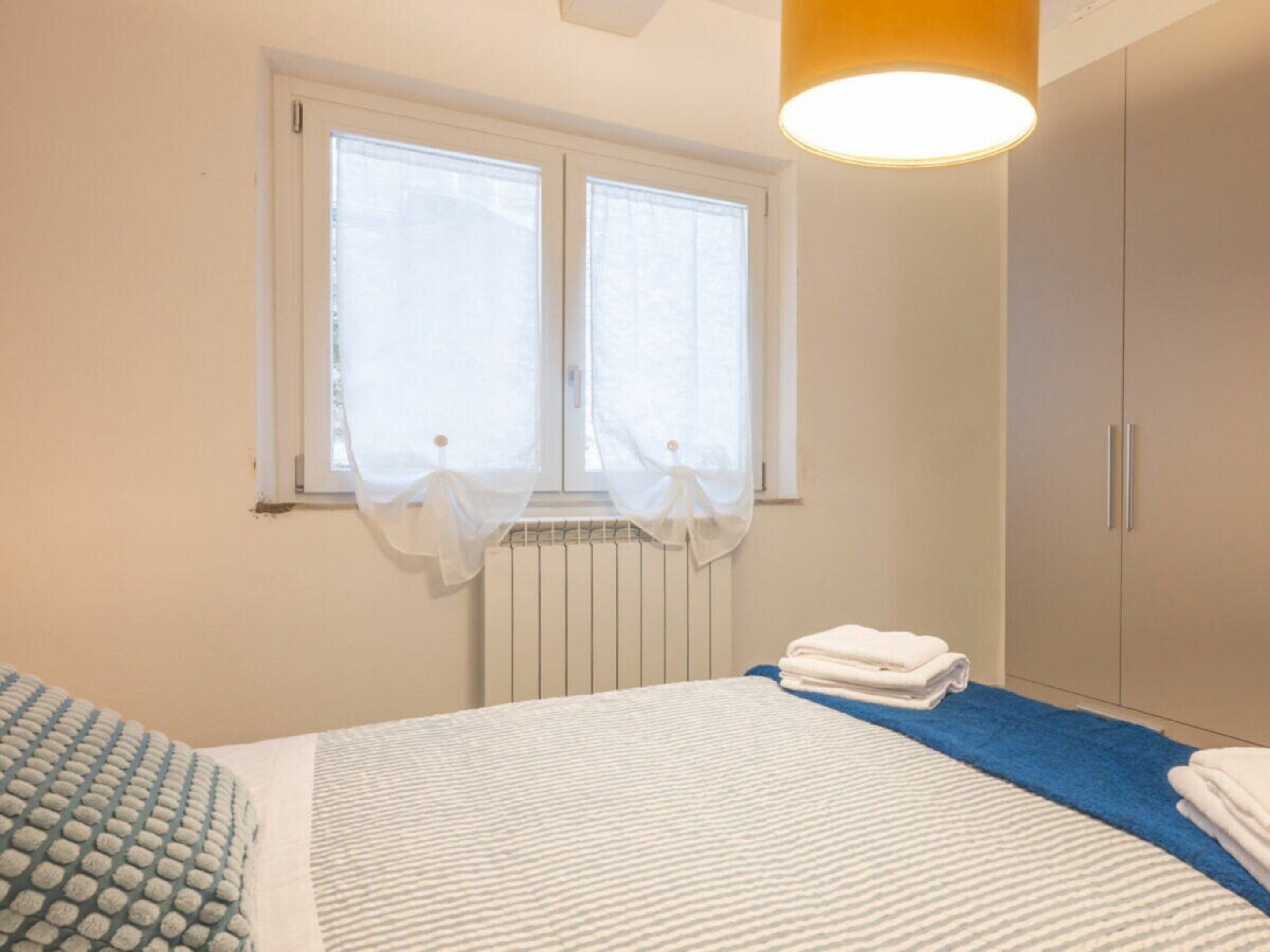 Una camera da letto con un letto, un termosifone, una finestra con tende e un armadio.