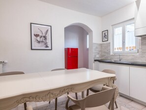 Eine moderne Küche mit Esstisch, Stühlen, einem roten Kühlschrank und Wanddekoration.