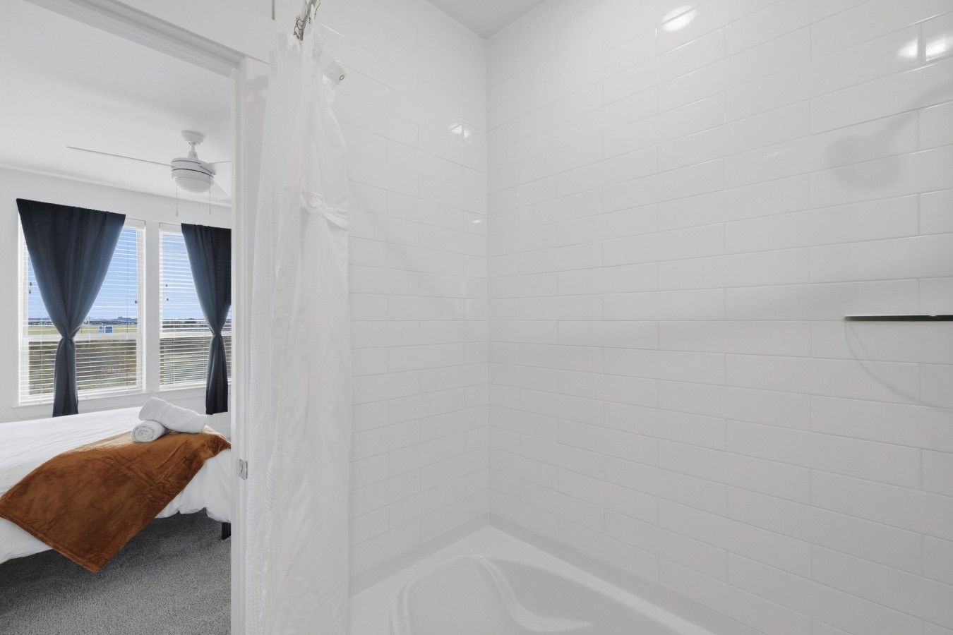 A bathroom with white tiled walls, a bathtub, and a shower curtain.