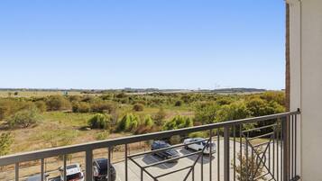 A balcony with a view of a parking lot and distant buildings.