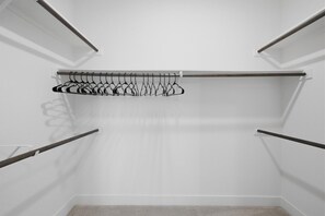 A walk-in closet with a metal rod rack and a hanging rod for clothes. - Beautiful 2BR near PGA and Universal Studios | Sleeps 6 (Frisco)