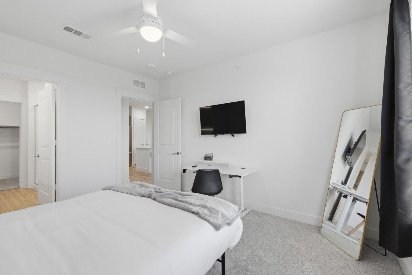 Une chambre à coucher avec un lit, un bureau, une chaise, une télévision et un miroir.