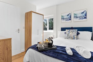 Une chambre d’hôtel avec un lit, une table de chevet avec une machine à café et deux tableaux accrochés au mur.