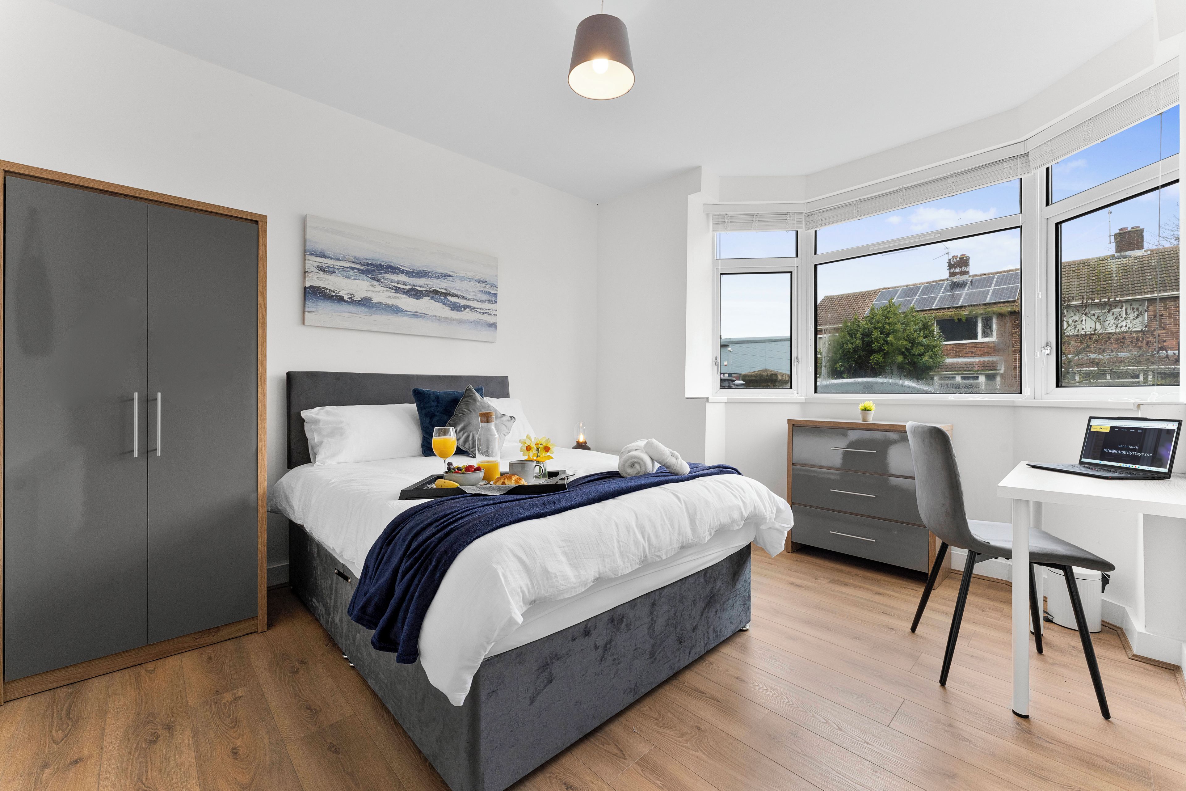 Een moderne slaapkamer met een bed, nachtkastje, bureau en uitzicht.