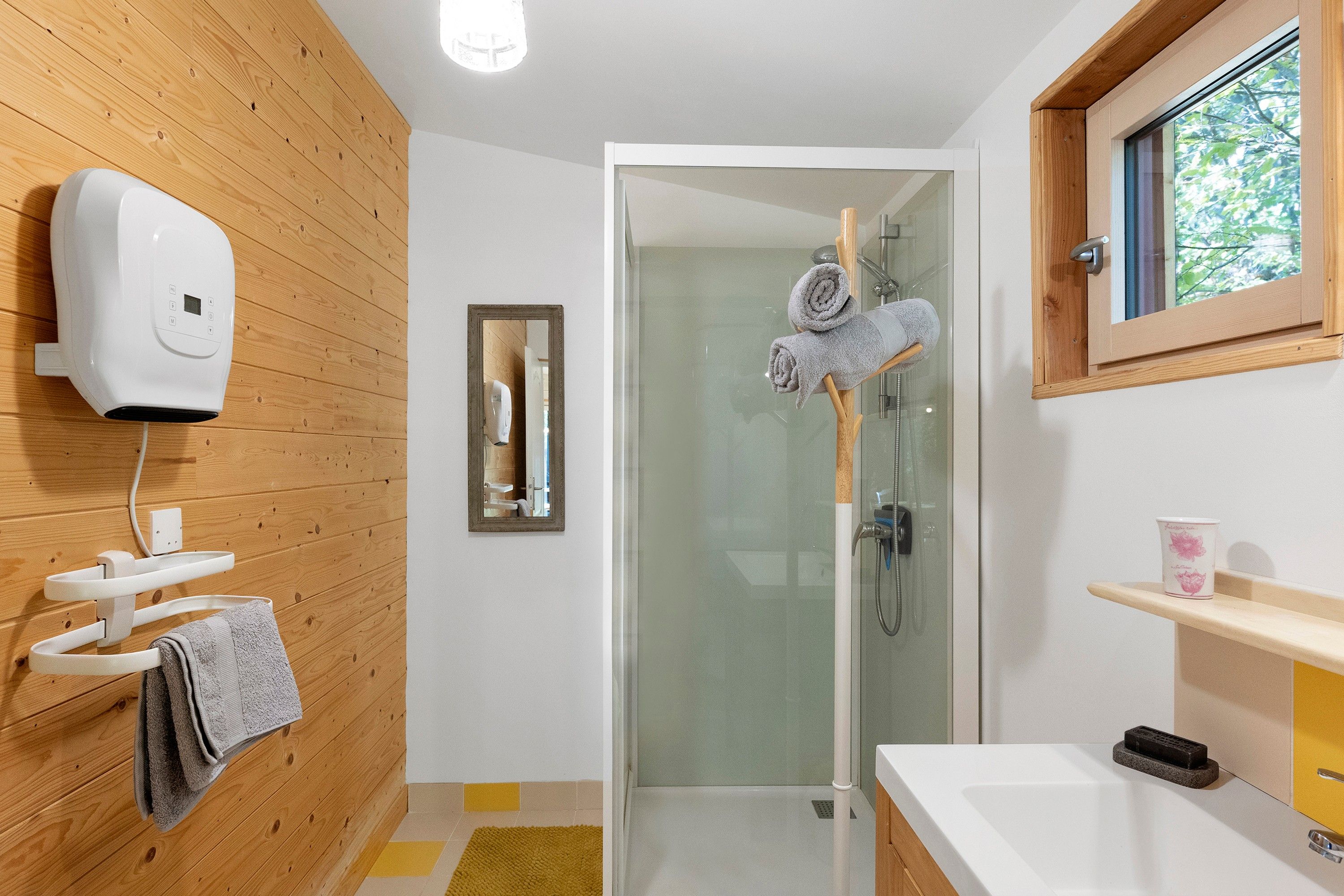 Une salle de bain moderne avec un mur en bois, une cabine de douche en verre, un lavabo blanc et un porte-serviettes.