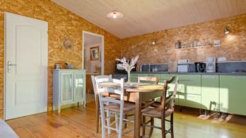 A wooden interior with a dining table, chairs, and a kitchen area with cabinets and appliances.
