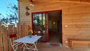 A wooden cabin with a patio table, chairs, and a bench. - Holiday Home 'Cabane De La Grande Ourse -' with Mountain View, Private Garden and Wi-Fi (Banne)