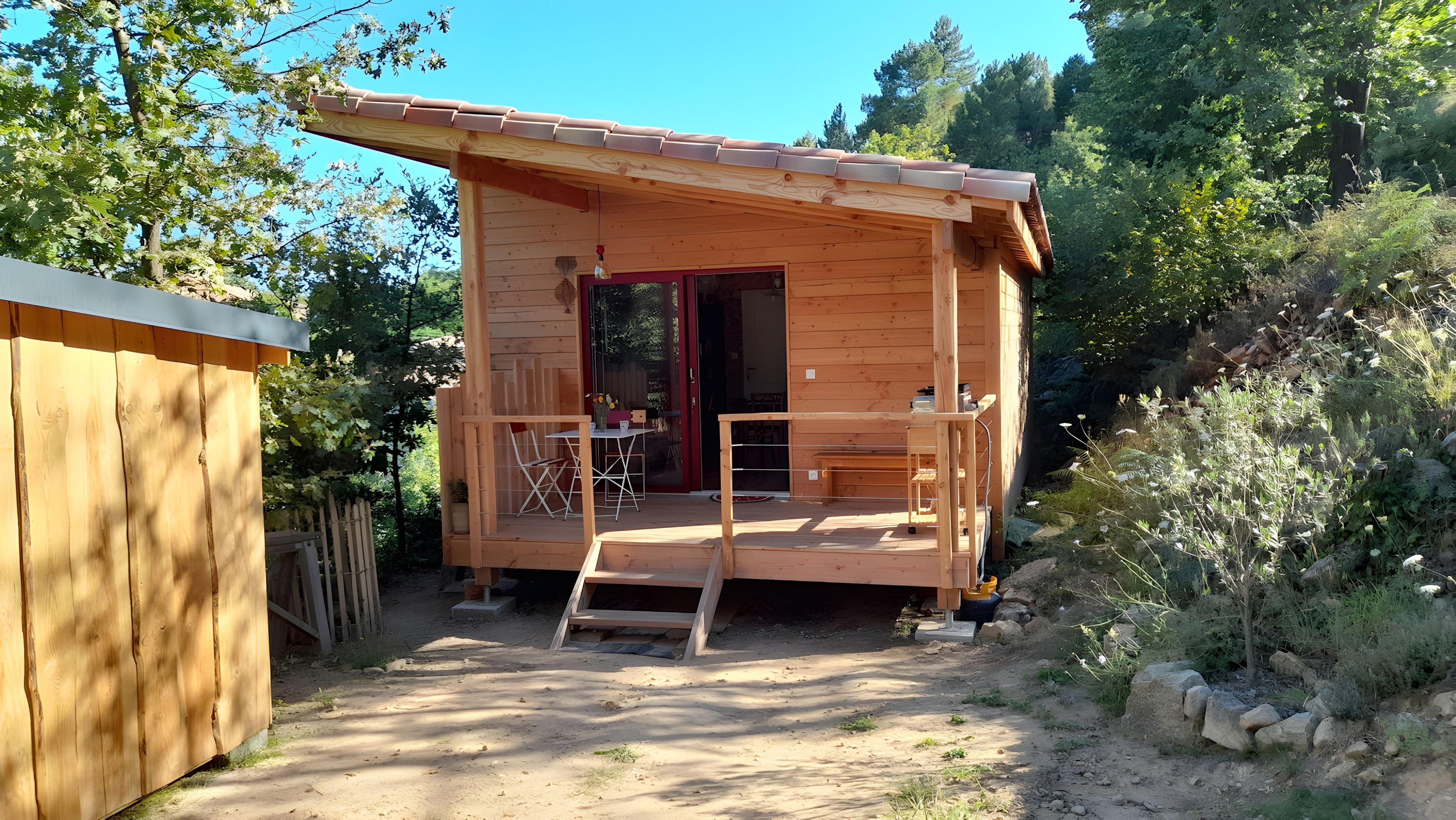 A wooden cabin with a porch, a door, and a small table with chairs.