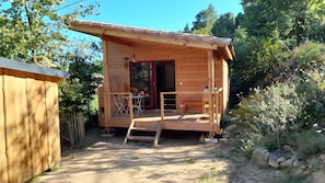 Eine Holzhütte mit Veranda, einer Tür und einem kleinen Tisch mit Stühlen.