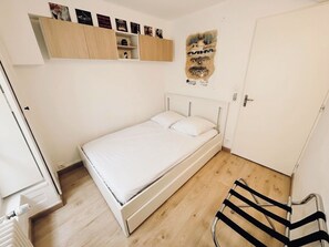 A bedroom with a single bed, a wooden cabinet above the bed, and a door to the right. - Apartment near Place des Terreaux, sleeps 4 (Lyon)