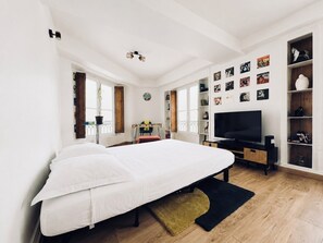 Een moderne slaapkamer met een groot bed, een televisie en een boekenplank.