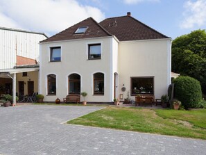 A two-story house with a tiled roof, a paved driveway, and outdoor seating. - on the Kahlcke Holiday Farm (Reinsbüttel)