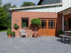 A brick building with a wooden door, a window, and a bench. - on the Kahlcke Holiday Farm (Reinsbüttel)