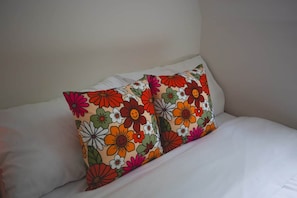 A bed with white bedding and two decorative pillows with a floral pattern.