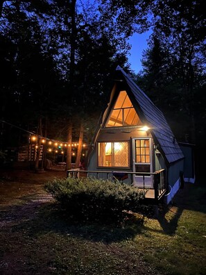 Eine Holzhütte mit einem Dreiecksdach, großen Fenstern und einer Veranda.