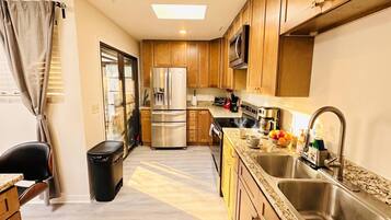 A compact kitchen with stainless steel appliances, wooden cabinets, and a granite countertop.