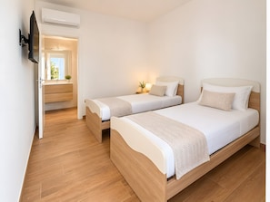 Una habitación de hotel con dos camas, televisión y baño con espejo.