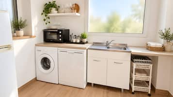 A compact kitchen with a washing machine, dishwasher, microwave, and a large window.