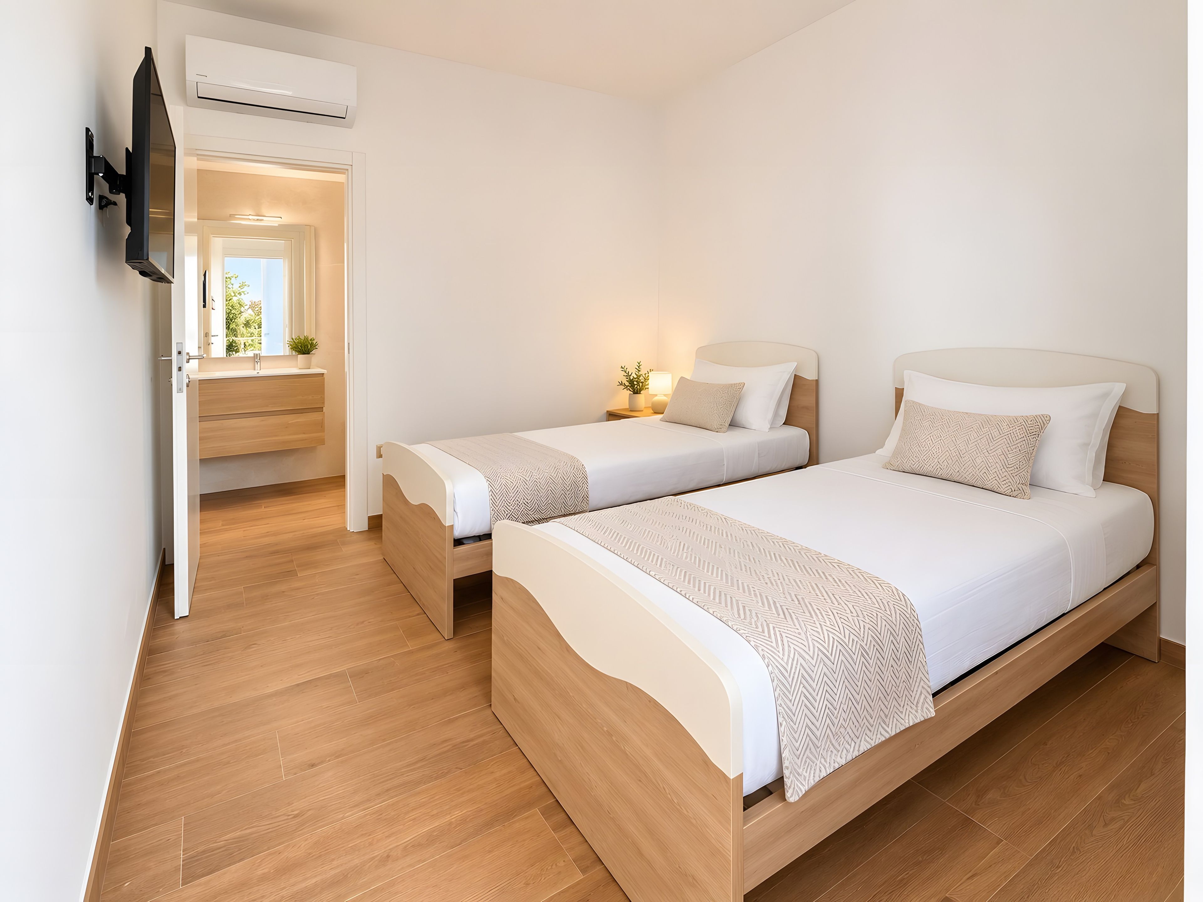 Ett hotellrum med två sängar, en TV och ett badrum med en spegel.