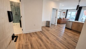 A modern kitchen with wooden flooring, a dishwasher, and a view of the city. - The James Suite Four | New 2BR Beach Block (Atlantic City)