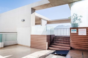 A modern building with a staircase leading to an upper level, a glass railing, and a sign indicating a pool without diving. - Kennedy Apartments by Andes STR (Santiago)