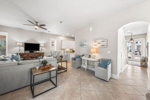 A modern living room with a grey sofa, a coffee table, and a TV. - Sunshine Shack (Panama City Beach)