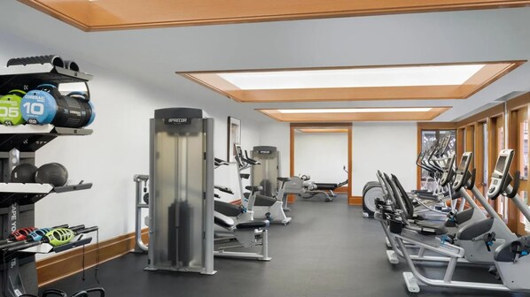 Ein Fitnessraum mit Laufbändern, Krafttrainingsgeräten und einer Spiegelwand.