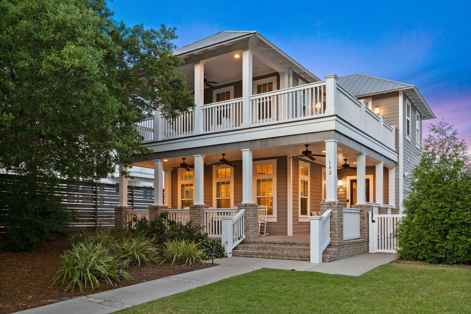 A two-story house with a balcony, a porch, and a well-maintained lawn.