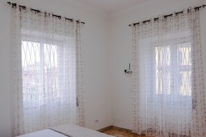 A room with two windows covered by sheer curtains, a bed, and a door with a handle. - Casa Tramonti (Napoli)