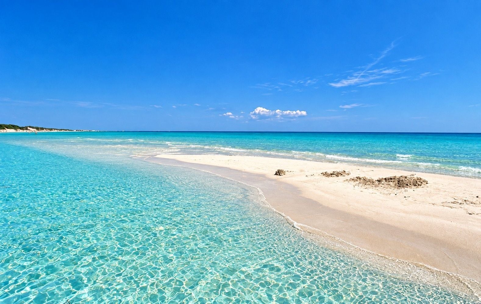 A beach with clear turquoise water and a sandy shore.