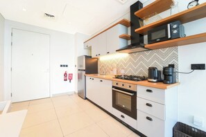Eine moderne Küche mit Gasherd, Mikrowelle und Einbauofen. Es gibt eine Holz Arbeitsplatte und eine Backspulane mit Fischgrätmuster.