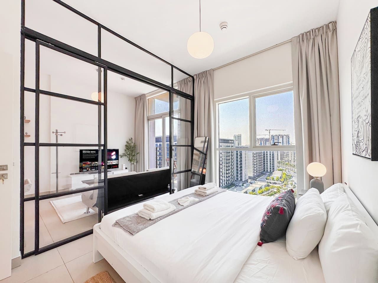Een moderne hotelkamer met een groot bed, een bureau, een televisie en uitzicht op de skyline.