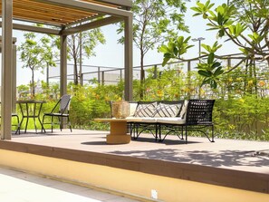 Ein Außenbereich mit Sitzgelegenheiten, einem Tisch, Stühlen und einer Bank, sowie einer Pergola.