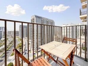 A balcony with a table and chairs, overlooking a cityscape with high-rise buildings. - Modern 1BR Retreat in Socio | Dubai Hills (Dubai)