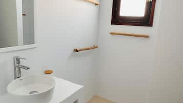 Ein Badezimmer mit einem weißen Waschbecken, einem Spiegel und Holzregalen.