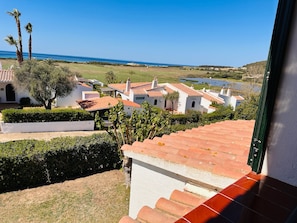 Un área residencial costera con edificios blancos, tejados de tejas rojas y una vista despejada del mar.