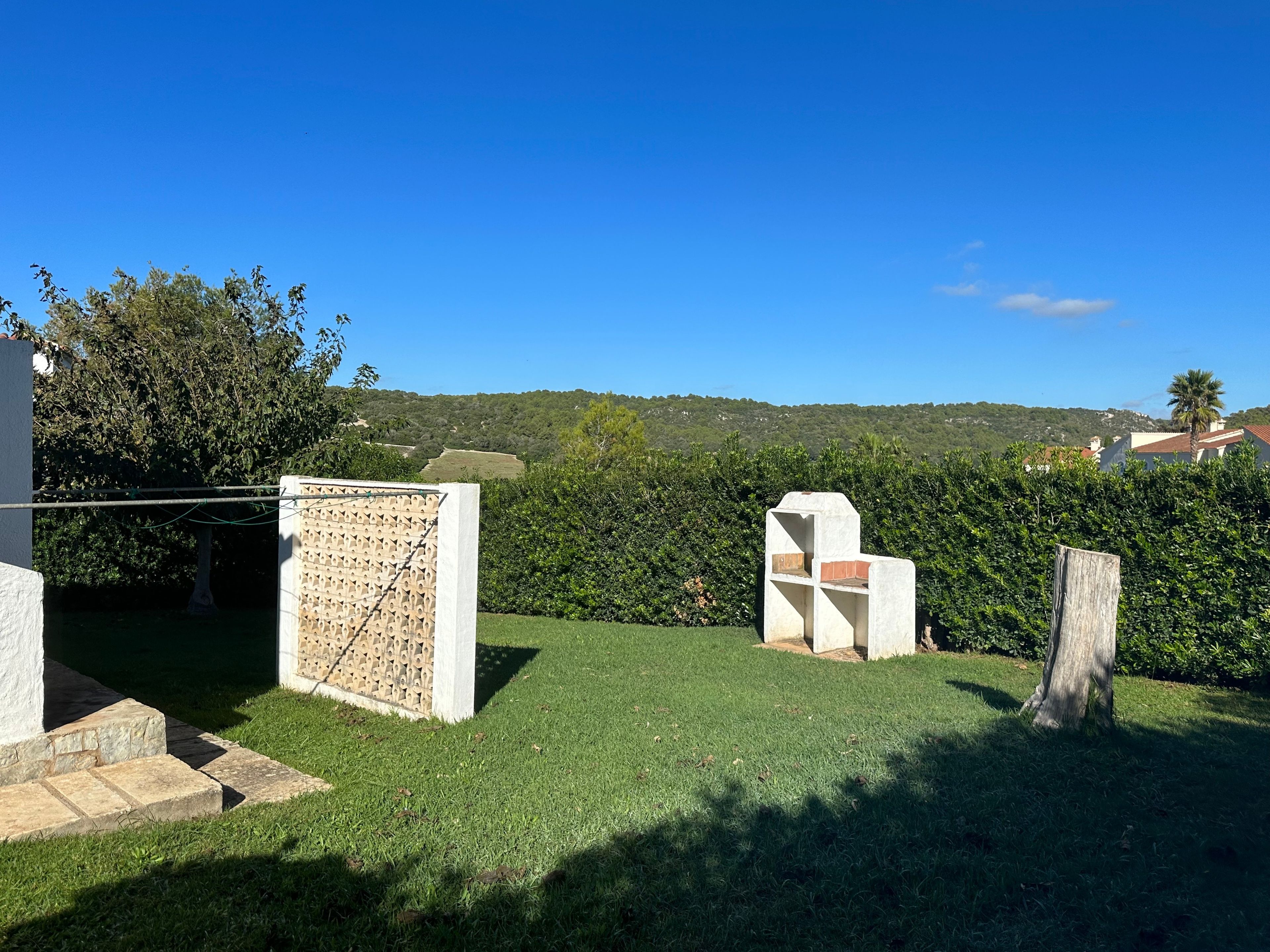 Un espacio al aire libre con césped, un muro de piedra y una valla de madera.