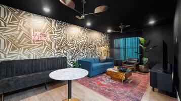 Ein modernes Wohnzimmer mit einer Wand mit Muster, einem blauen Sofa, einem runden Couchtisch und einem großen Fenster.