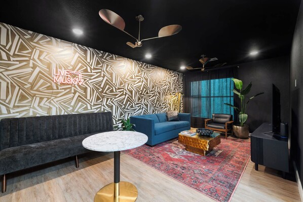 Ein modernes Wohnzimmer mit einer Wand mit Muster, einem blauen Sofa, einem runden Couchtisch und einem großen Fenster.