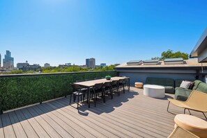 Una terraza en la azotea con vistas al horizonte de la ciudad, una mesa con sillas y un sofá.