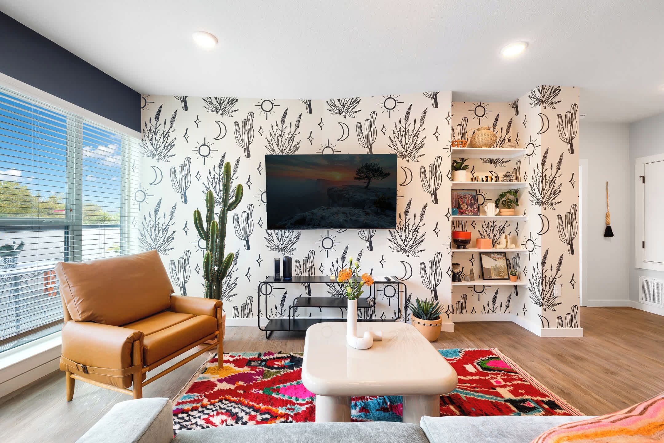 Ein modernes Wohnzimmer mit Ledersessel, Couchtisch, Wandfernseher und einer Sukkulente.