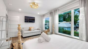 Ein Hotelzimmer mit Bett, einer Couch, einem Gemälde, einem Fenster mit Blick und einer Leiter.