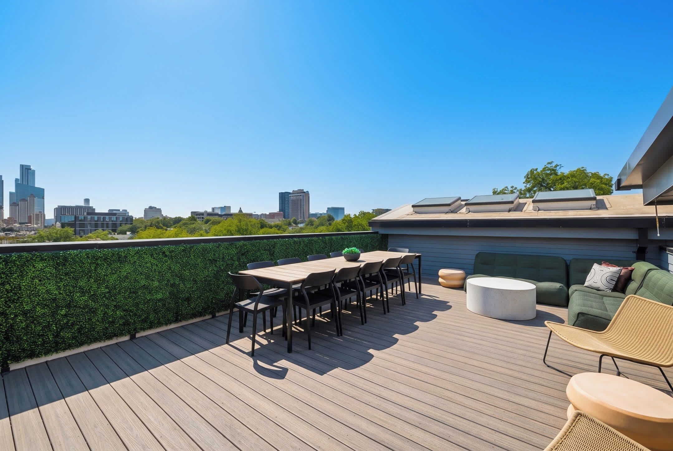 Eine Dachterrasse mit Blick auf die Skyline der Stadt, einem Tisch mit Stühlen und einer Couch.